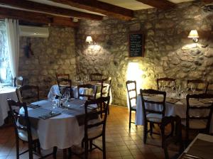 Montpezat-sous-Bauzon蒙佩扎宾馆的一间带桌椅和石墙的用餐室