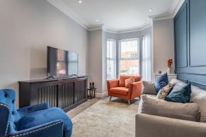 贝尔法斯特Luxury Edwardian Townhouse in Belfast的客厅配有电视、沙发和椅子