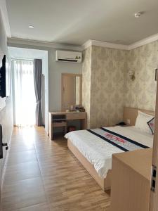迪石Ngoc Thanh Hotel的一间卧室配有一张床、一张书桌和一个窗户。