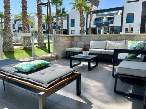 奥里韦拉海滩Casa La Zenia的一个带沙发和椅子的庭院,并种植了棕榈树。