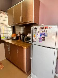 波德申Glory beach private PD的厨房配有白色冰箱和木制橱柜。