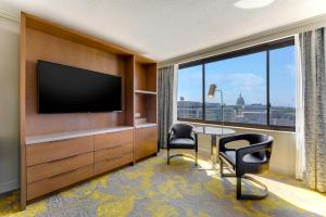华盛顿Hilton Washington DC Capitol Hill的酒店客房配有电视、桌子和椅子。