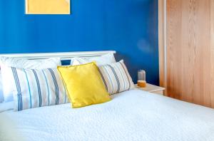 拉巴特Luxury Apartment 3 Bedroom in the Heart of Agdal near Arribat Center的一间卧室设有蓝色的墙壁和一张带黄色枕头的床。