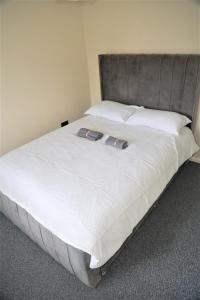 ChurchdownLuxe Cosy&Spacious 2 Bed House - Super Fast Wi-Fi & Private Parking Near GLO Airport & Cheltenham Racecourse的一张配有白色床单和灰色床头板的大床