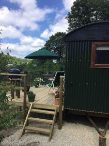 LonghopeShepherd's Hut. Shower & WC. Deck. Amazing view的木甲板配有桌子和遮阳伞