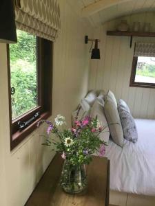LonghopeShepherd's Hut. Shower & WC. Deck. Amazing view的卧室,桌子上放着花瓶