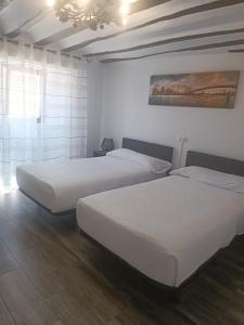 QuintanapallaHotel Rural Quintanapalla的配有白色墙壁和木地板的客房内的两张床