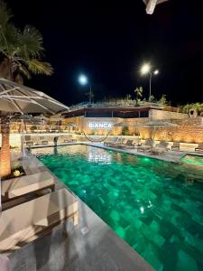 地拉那Bianca Hotel & Villa的夜间游泳池,配有椅子和灯