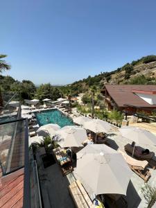 地拉那Bianca Hotel & Villa的度假村设有带遮阳伞和桌椅的游泳池