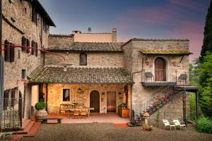 潘札诺La Pensione di Vignamaggio的一座古老的石头房子,设有庭院和一张桌子