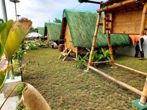 丹辘Unlimited Pax Bale Kubo-inspired Accommodation的草屋顶和草棚的小屋
