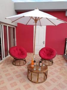 塔那那利佛Appartements Andrian Location的两张红色的椅子和一张带雨伞的桌子