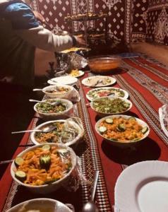 瓦迪拉姆Wadi Rum Story Camp的一张桌子上放着许多碗食物