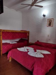 米娜克拉韦罗Hotel 20 de Junio的宿舍间内的两张床,配有红色床单和风扇