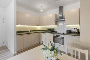 伦敦Centrally Located Modern 2Bed 2Bath Apartment的厨房配有白色橱柜和花瓶