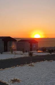 达纳Dana Sunset Eco Camp的沙漠中的房屋,背景是日落