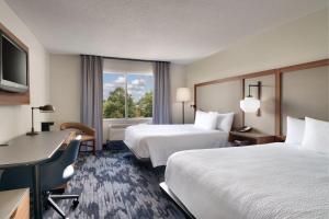 奥尔巴尼Fairfield Inn & Suites by Marriott Albany的酒店客房设有两张床、一张书桌和一个窗户。