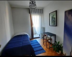 特伦托Verdisuite - Trento centro - Parcheggio privato gratuito的一间卧室配有一张蓝色的床和一张桌子