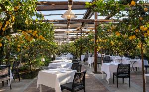阿纳卡普里卡萨玛丽安冬妮娅精品酒店的一间拥有白色桌椅和橘子树的餐厅