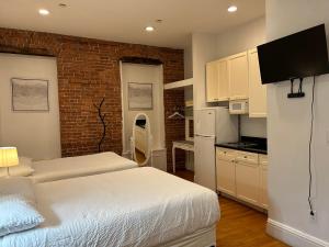 纽约Hansem stay的一间带两张床的卧室和一间带白色橱柜的厨房