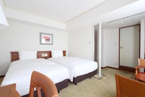 名古屋KOKO HOTEL Nagoya Sakae的酒店客房设有两张床和一张桌子。