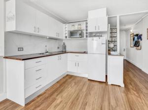 黄金海岸Beachfront Studio的白色的厨房配有白色橱柜和木地板