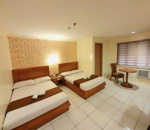 马尼拉Rosas Garden Hotel的酒店客房设有两张床和一张桌子。