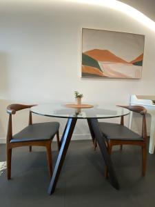 堪培拉Stylish Central Lake View Apartment的一张玻璃桌,配有两把椅子和一张桌子,还有一幅画