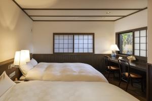 由布市汤布院茶寮日式旅馆的一间卧室设有两张床、一张桌子和窗户。