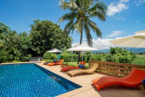 范县Baan innto resort的一个带椅子和遮阳伞的游泳池以及棕榈树