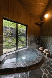 由布市汤布院茶寮日式旅馆的带大窗户的客房内的热水浴池