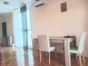 Novi BeogradComfort Apartment的一间带木桌和白色椅子的用餐室