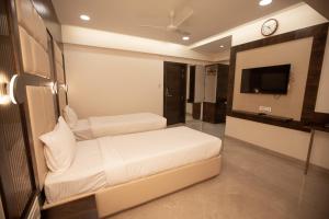 孟买Hotel Naaz Executive的一间酒店客房,设有两张床和电视