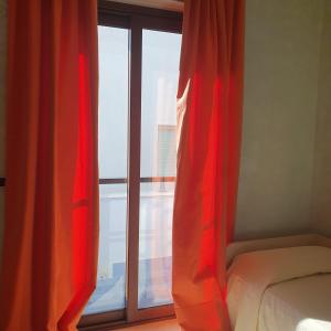 玛格丽塔萨沃亚瑞纳里餐厅酒店的一间卧室设有窗户,配有红色窗帘和一张床