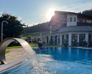 拜尔斯布龙Wellness & Genuss Resort - Engel Obertal的一座房子前面的游泳池,喷泉