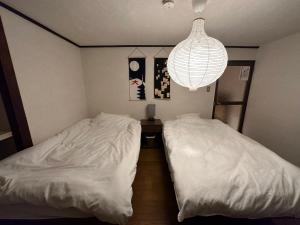 奈良奈良公園徒歩15分古民家リノベーション貸切一軒家 Guest House奈良紀寺的一间卧室配有两张床和吊灯。