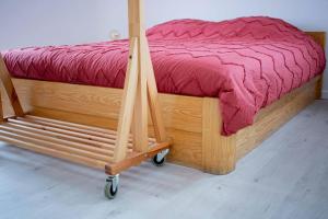 Maison Raymond - Vakantiehuisje met houtgestookte sauna的木车上的木床和红色的被子
