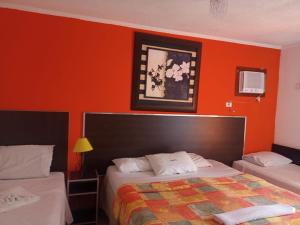 瓜鲁雅Astúrias Praia Hotel的一间卧室设有两张床和橙色的墙壁