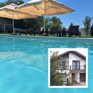 Popeşti-LeordeniCosy 3 bedroom house with pool的一个带遮阳伞和房子的游泳池