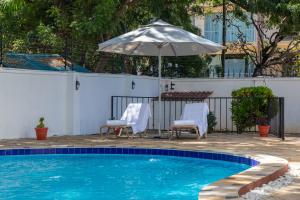 达累斯萨拉姆Upendo Boutique Hotel, Dar es Salaam的一个带两把椅子和遮阳伞的游泳池
