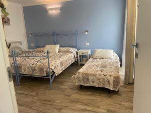 科利科Corte del Lago的配有蓝色墙壁和木地板的客房中的两张床