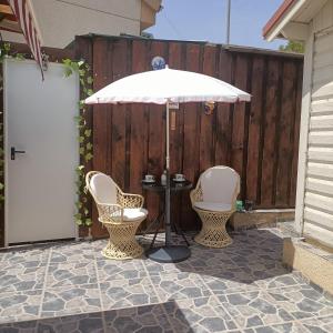 克萨达城Cottage in Ciudad Quesada的庭院里设有两把椅子和一张桌子及一把遮阳伞