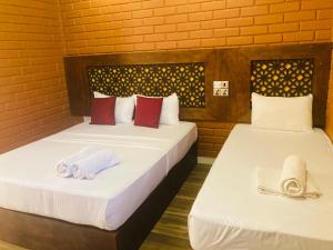 阿努拉德普勒Monaara Leisure - Anuradhapura的客房内的两张床和毛巾