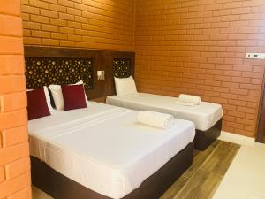 阿努拉德普勒Monaara Leisure - Anuradhapura的砖墙客房的两张床
