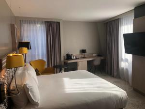 马西Hilton Garden Inn Paris Massy的酒店客房配有一张床、一张书桌和一台电脑