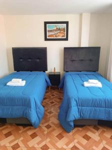 利马A y J Familia Hospedaje的配有蓝色棉被的客房内的两张床