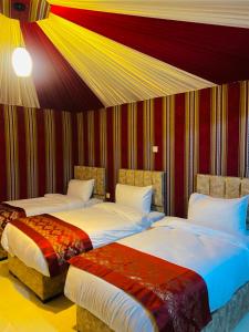 瓦迪拉姆Syndebad desert camp的一间卧室设有两张床和条纹墙