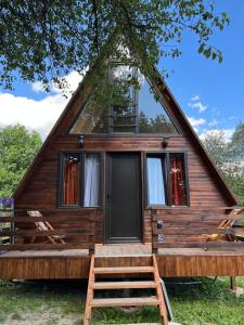 梅斯蒂亚Cottage Mida的小屋设有茅草屋顶、门廊和2把椅子