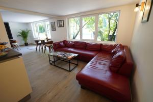 埃希特纳赫B&B Alferweiher的客厅配有红色皮革沙发和桌子