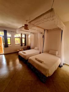 姆巴拉拉GKAT Resort的一间卧室配有两张床、白色床单和窗户。